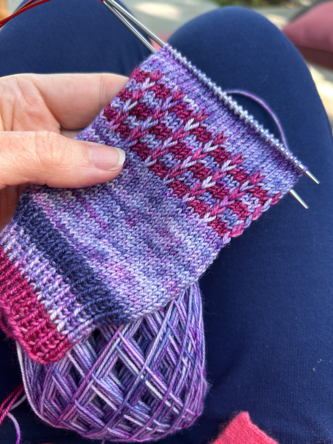 a hand knit sock in progress in the colors purple, blue, and magenta