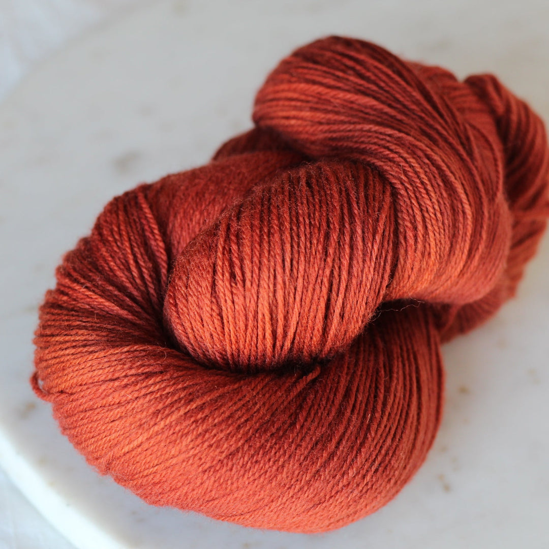 Ball of rust orange yarn on a white plate