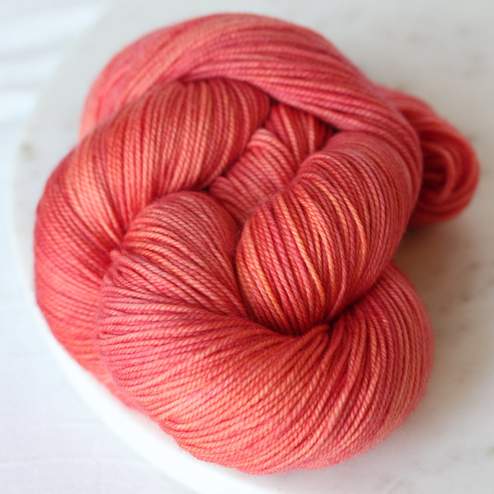 coral pink skein of yarn on light marble background