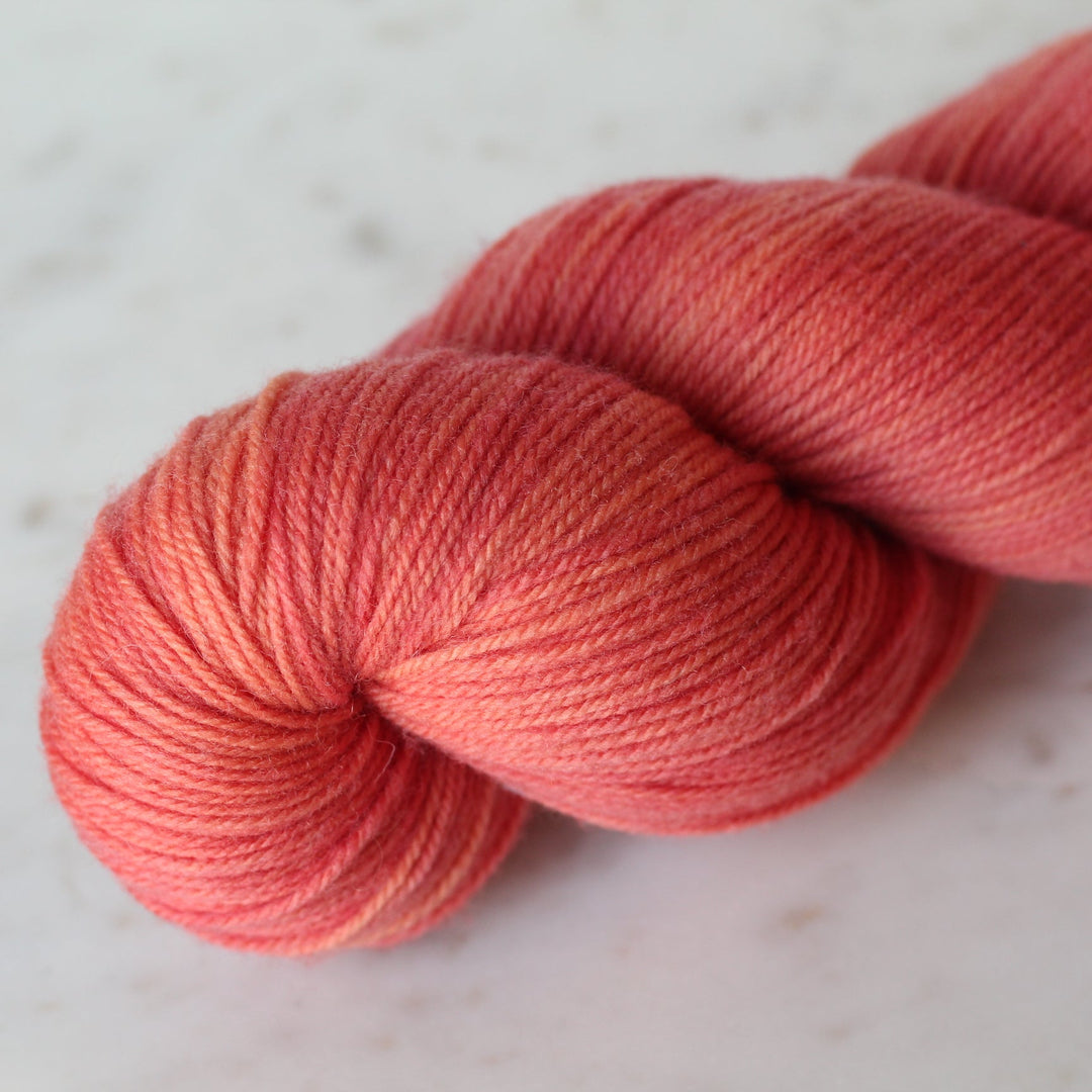 Ball of coral pink yarn on a light background
