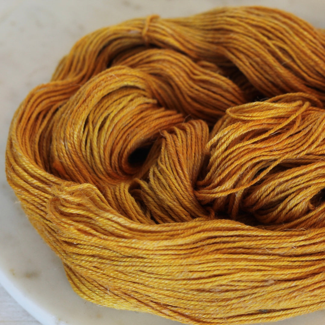 Ball of yellow yarn on a white marble surface