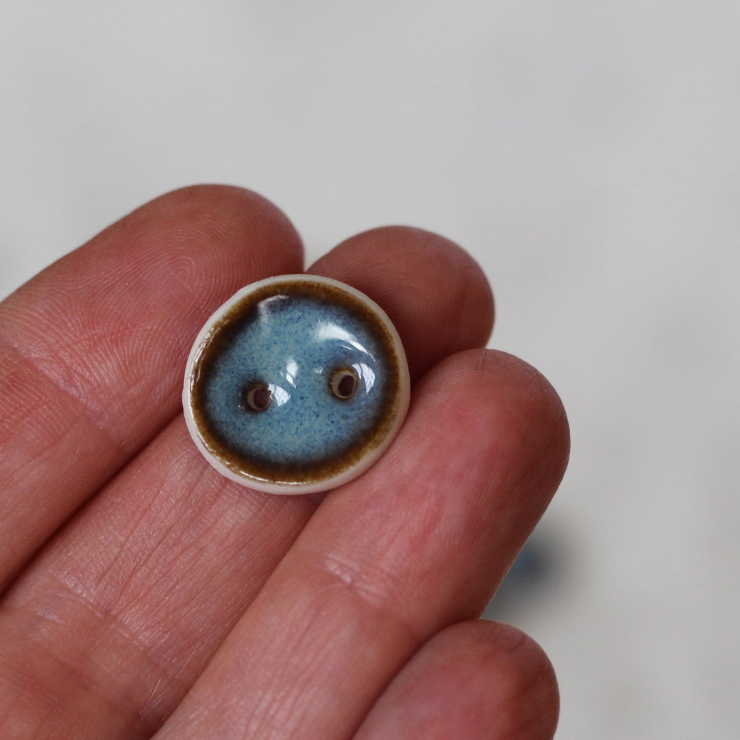 Small ceramic object with a blue interior held in a hand against a white background