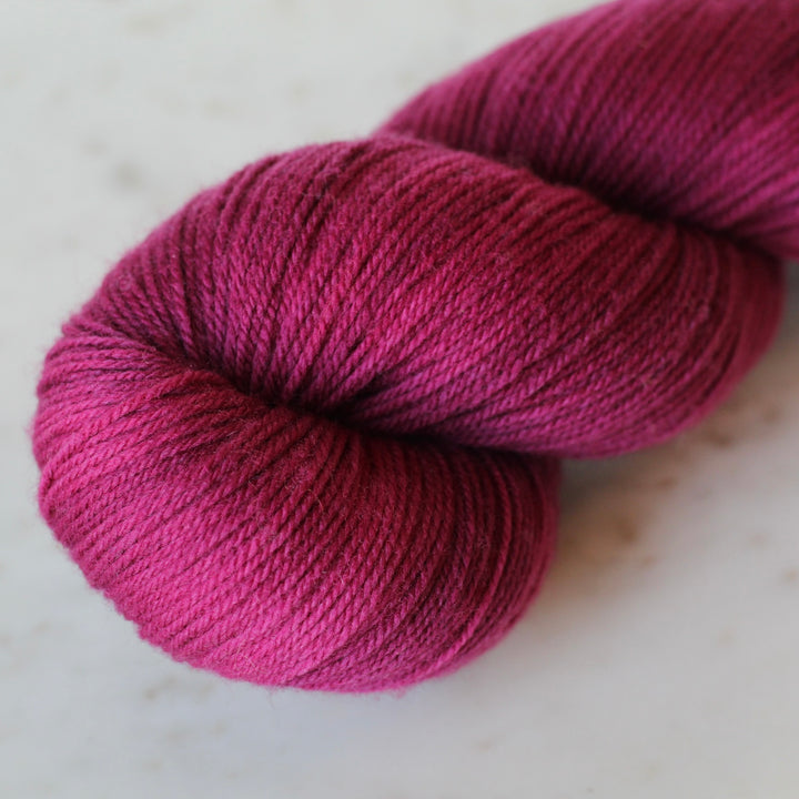 Magenta skein of yarn on a light surface