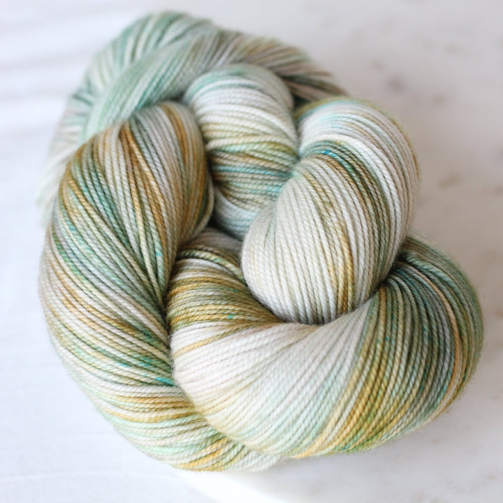 Soft Green, mint, and gold yarn on light background