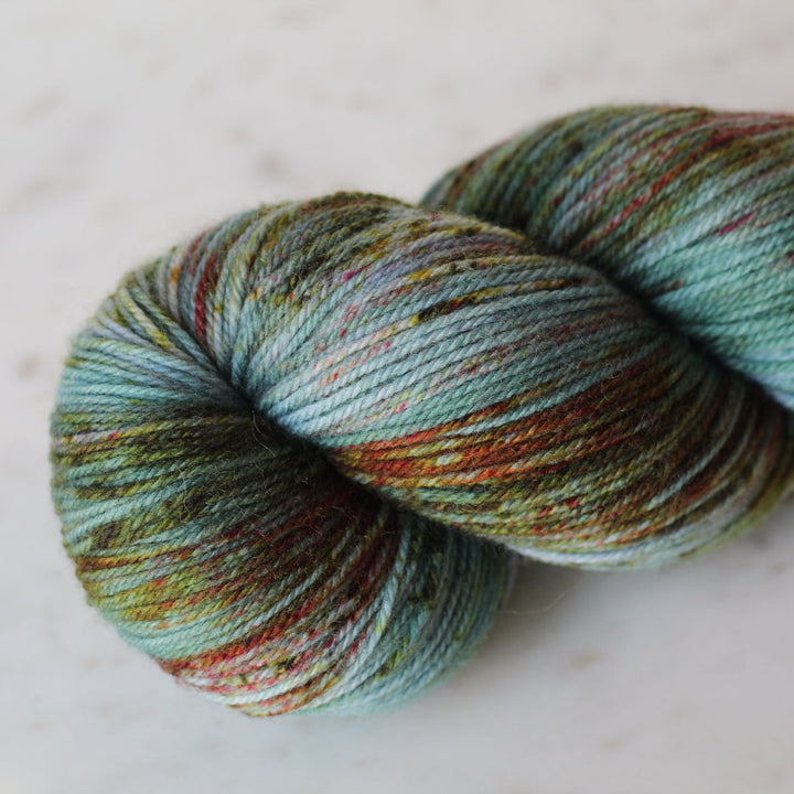 Multicolored teal skein of yarn on a white surface