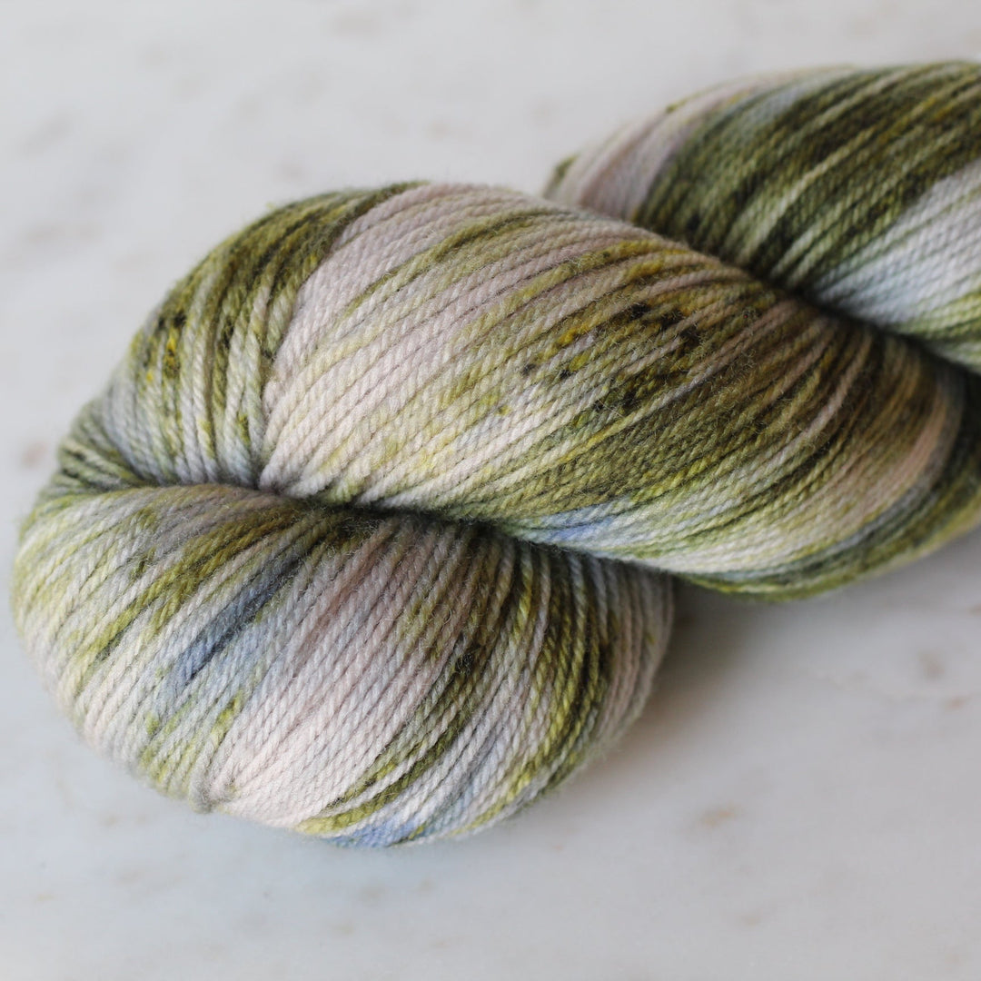 Multicolored green and blue skein of yarn on a white marble surface
