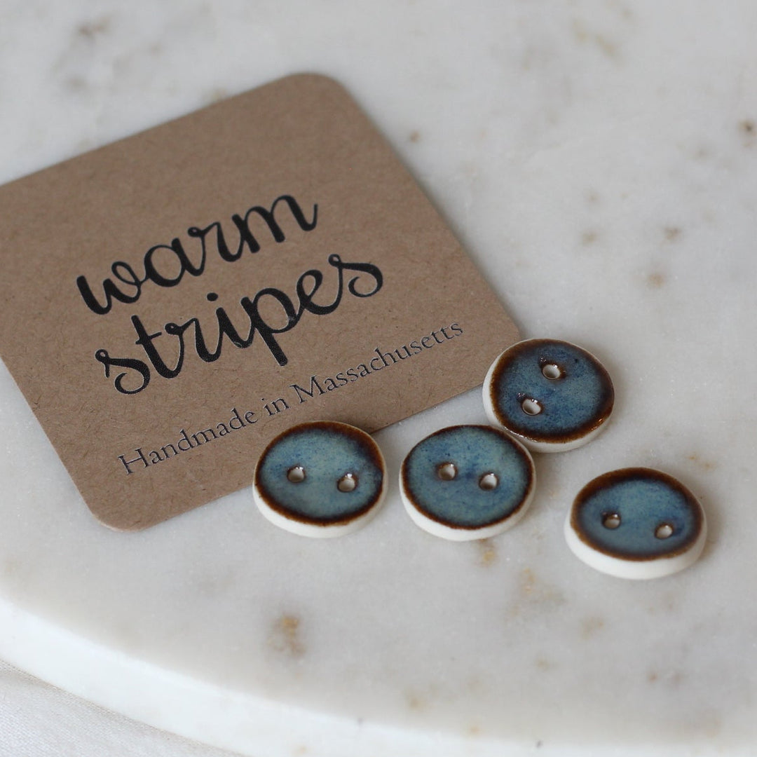 Set of small round buttons with a 'warm stripes' label on a marble surface