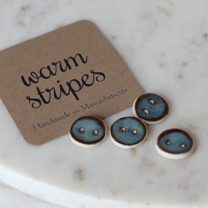 Set of small round buttons with a 'warm stripes' label on a marble surface